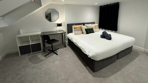 Una camera da letto moderna con un letto, una scrivania, una sedia e uno specchio grande.
