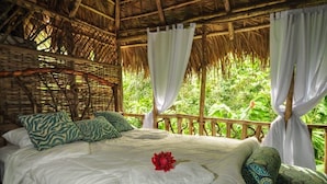 A bed with a white bedspread, green patterned pillows, and a red flower decoration. - Samana Tropical with DodoMap (Samaná)
