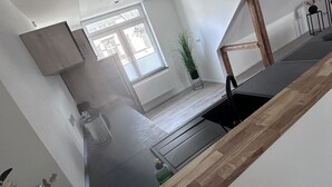 A modern kitchen with a wooden countertop, a built-in oven, and a window with blinds. - Ferienwohnung in Obernkirchen (Obernkirchen)
