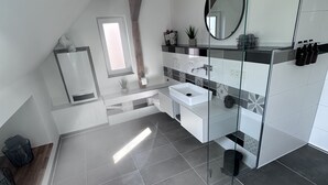 A modern bathroom with a glass shower enclosure, a white sink, and a large mirror. - Ferienwohnung in Obernkirchen (Obernkirchen)