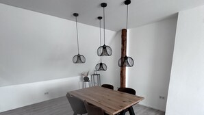 A dining area with a wooden table, four chairs, and hanging pendant lights. - Ferienwohnung in Obernkirchen (Obernkirchen)