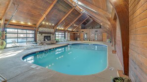 An indoor swimming pool with wooden beams, a stone fireplace, and lounge chairs. - Lakefront Condo w/ Resort Amenities in Osage Beach (Osage Beach)