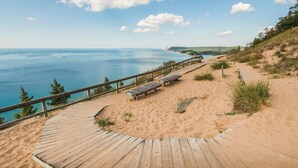A wooden boardwalk leading to a sandy beach with benches and a railing overlooking the sea. - Brand New Beautiful 3 BDR Home Unit 838  (Traverse City)
