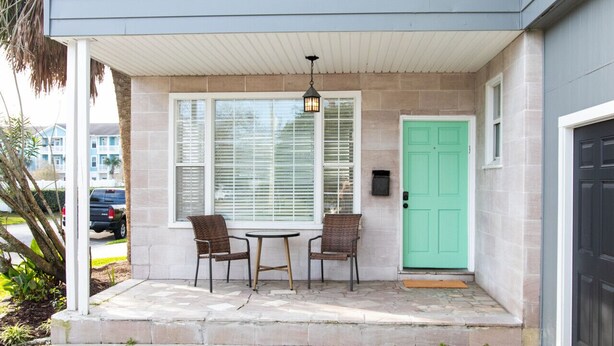 A covered porch with two chairs and a table, a green door, and a mailbox. - NEW Listing! In the Heart of Jax Beach (Jacksonville Beach)