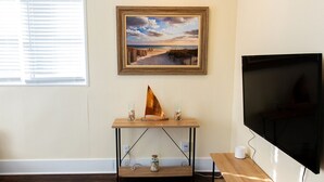 A room with a wooden table, a painting, a TV, and a window with blinds. - NEW Listing! In the Heart of Jax Beach (Jacksonville Beach)