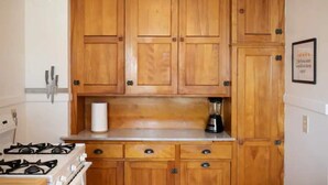 Une cuisine avec des armoires en bois, une cuisinière à gaz et un mixeur sur le plan de travail.