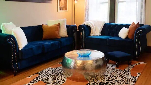 Un salon avec deux canapés bleu foncé, une table basse ronde en verre et un tapis à motifs léopard.