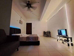 A bedroom with a bed, a desk, a chair, a television, and a ceiling fan. - i-Soho i-CityLED Homestay (Shah Alam)