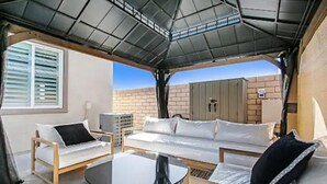 Een zonnig terras met een bank, stoelen en een tafel.