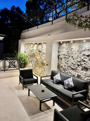 An outdoor seating area with a sofa, chairs, and a table, set against a textured wall. - Luxury house Prestige (Split)