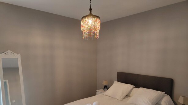 Ein Schlafzimmer mit einem großen Bett, einem Nachttisch, einer Kommode und einer Chandelier.