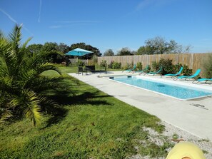 Relax by the clear pool surrounded by lounge chairs and lush greenery.