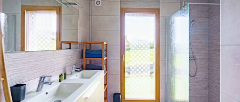 Ein modernes Badezimmer mit einem großen Waschbecken, einem Spiegel und einer Dusche.
