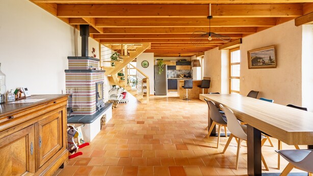 A spacious kitchen with a wooden ceiling, a dining area with a long table and chairs, and a staircase leading to an upper level. - Ty Jane Dour - Maison avec jardin (Plouhinec)