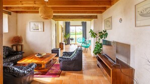 A spacious living area with a wooden ceiling, leather sofas, a wooden coffee table, and a TV on a wooden stand. - Ty Jane Dour - Maison avec jardin (Plouhinec)