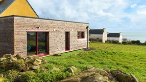 A modern house with a sloped roof, large glass doors, and a grassy lawn. - Ty Jane Dour - Maison avec jardin (Plouhinec)
