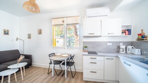 A modern kitchen with white cabinets, a dining table with chairs, and a large window with a view of trees.