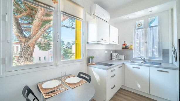 A modern kitchen with white cabinets, a built-in oven, and a window with a view of a tree and buildings.