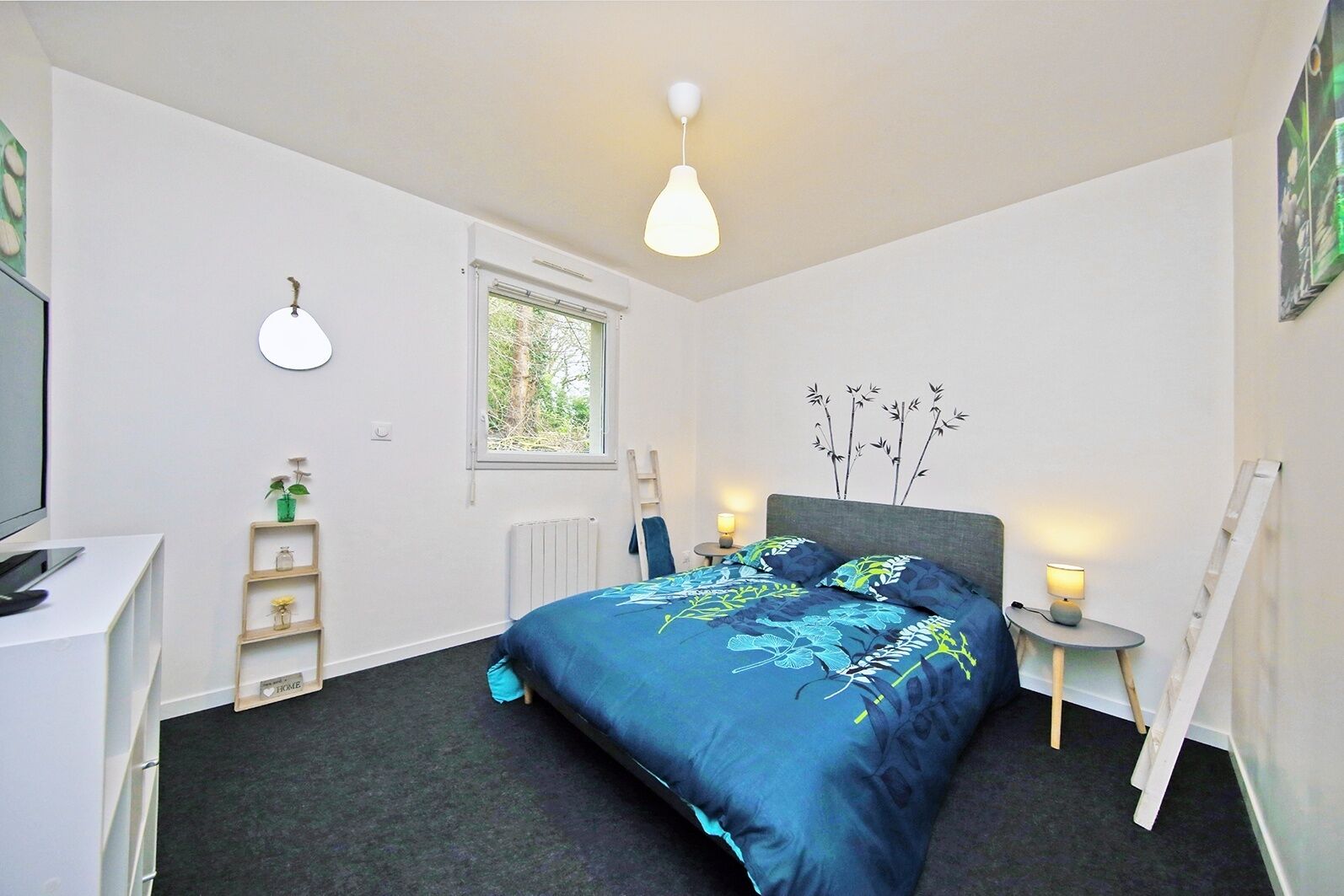 A bedroom with a bed, bedside tables, a desk, a window, and a radiator.