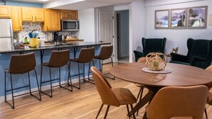 Una cucina moderna con mobili in legno, un'isola centrale con sgabelli da bar e un'area pranzo con tavolo rotondo e sedie.