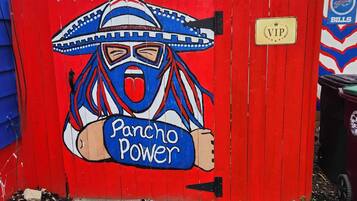 Una puerta roja con un mural de una figura enmascarada y la inscripción 'Pancho Power'.