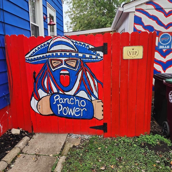 A red gate with a mural of a masked figure and the words "Pancho Power".