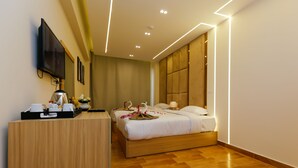 A hotel room with a wooden desk, a bed with a headboard, and a television mounted on the wall. - Rizk Pyramids View Hotel (Giza)