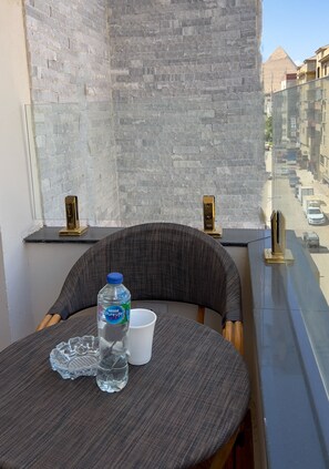 A balcony with a table, a water bottle, and a cup. - Rizk Pyramids View Hotel (Giza)