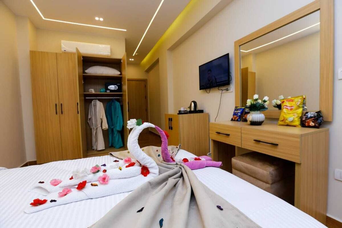 Una habitación de hotel con cama, televisión, escritorio con espejo y armario.