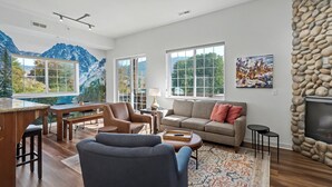 Un salon spacieux doté d’une grande fenêtre, d’une cheminée en pierre et d’un coin salon confortable.