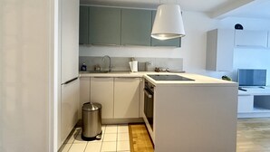 Une cuisine moderne avec des meubles blancs, une poubelle en acier inoxydable et un lave-vaisselle encastré.