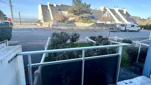 On voit un bâtiment avec un toit en pente, un panneau de signalisation indiquant un arrêt obligatoire et un fourgon blanc garé dans la rue.