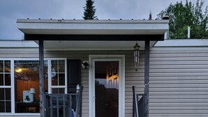 A house with a front porch, a wooden bench, and a set of steps leading to the door. - Cozy home in the heart of the Allagash.  Great for fishing, hiking, hunting, ect (Allagash)