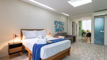 Um quarto moderno com cama de madeira, abajures, manta azul e um quadro na parede.