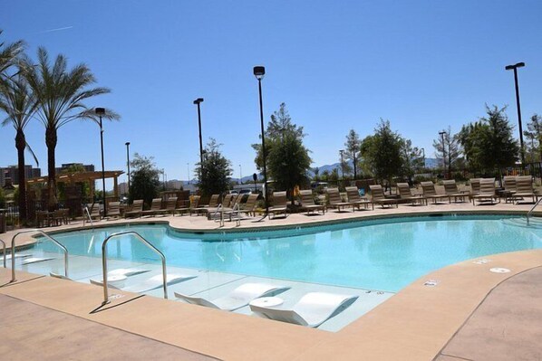 A swimming pool with lounge chairs and palm trees. - The Berkley (Las Vegas)