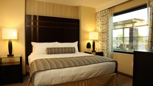A hotel room with a large bed, two bedside tables, a nightstand, a window with a view, and a decorative headboard. - The Berkley (Las Vegas)