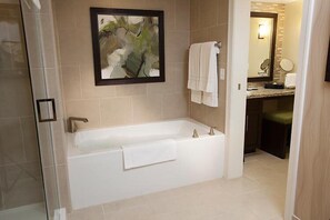 A modern bathroom with a bathtub, a framed abstract painting, and a vanity with a mirror. - The Berkley (Las Vegas)