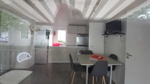 Cocina compacta con comedor, televisor montado en la pared y ventana con vistas al exterior.