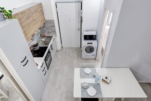 A compact kitchen with a microwave, washing machine, and sink. - Grazioso Moderno Monolocale San Donato - Vicino Metro Principi Dacaja (Torino)
