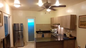 A kitchen with a refrigerator, microwave, stove, and a ceiling fan. - Beachfront Nature Rentals. Private Ground Floor Studio in Guesthouse (Quebro, District of Mariato)