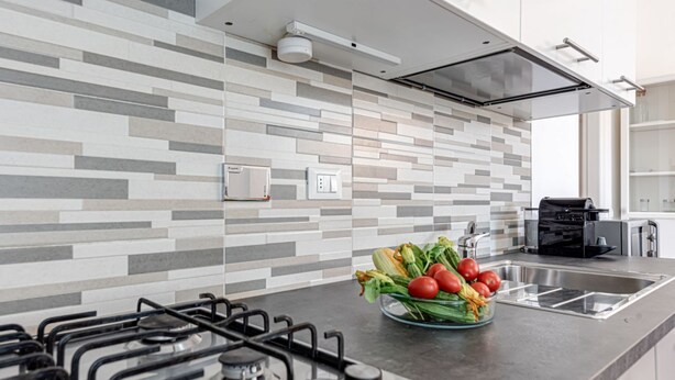 A modern kitchen with a gas stove, a stainless steel sink, and a tiled backsplash.