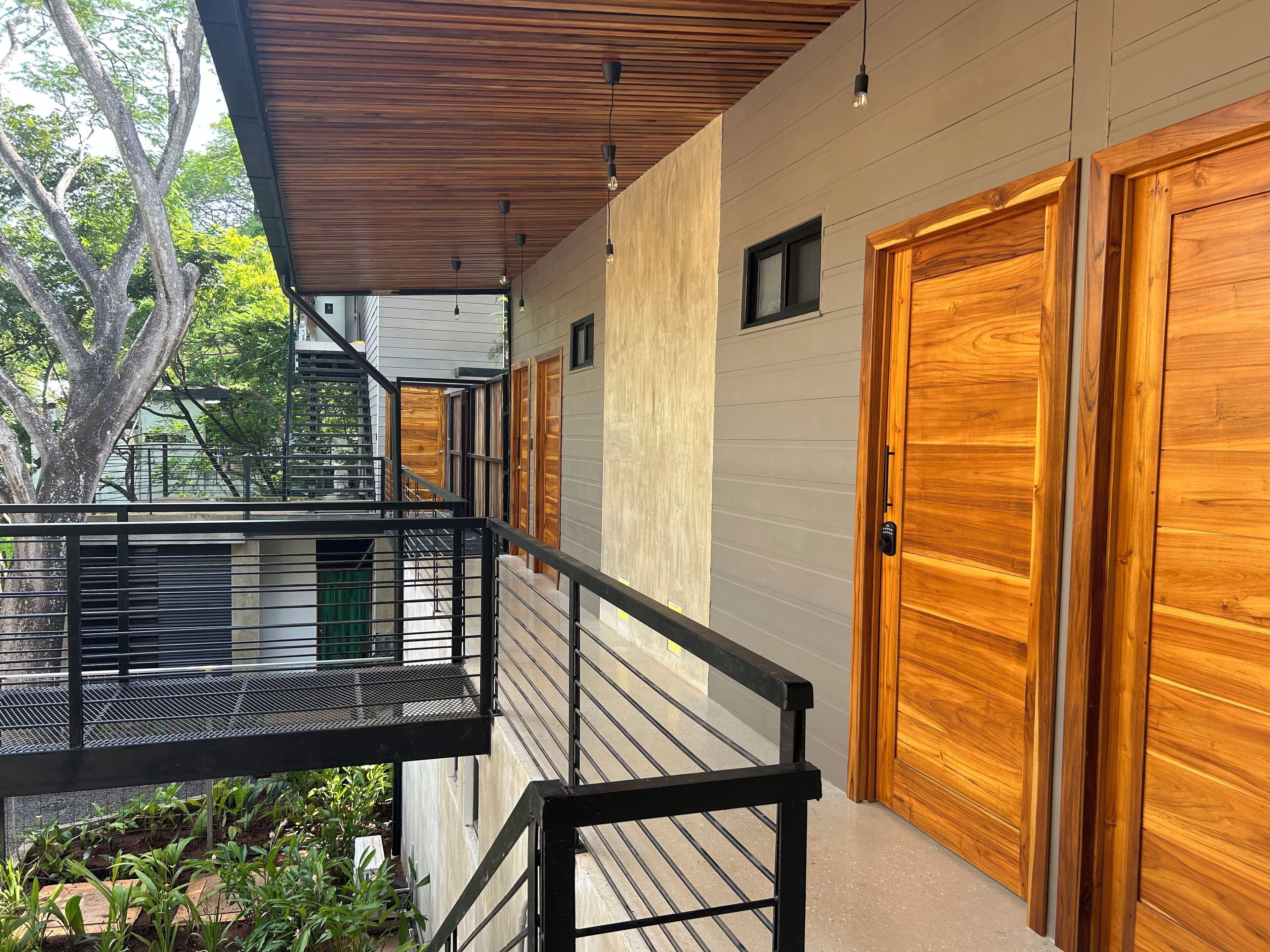 A modern building with a wooden door, a balcony with a metal railing, and a staircase.