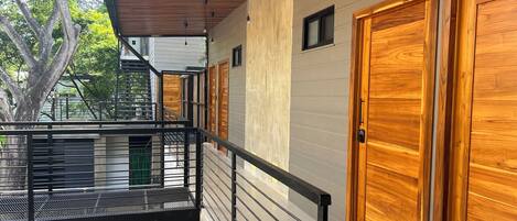 A modern building with a wooden door, a balcony with a metal railing, and a staircase.