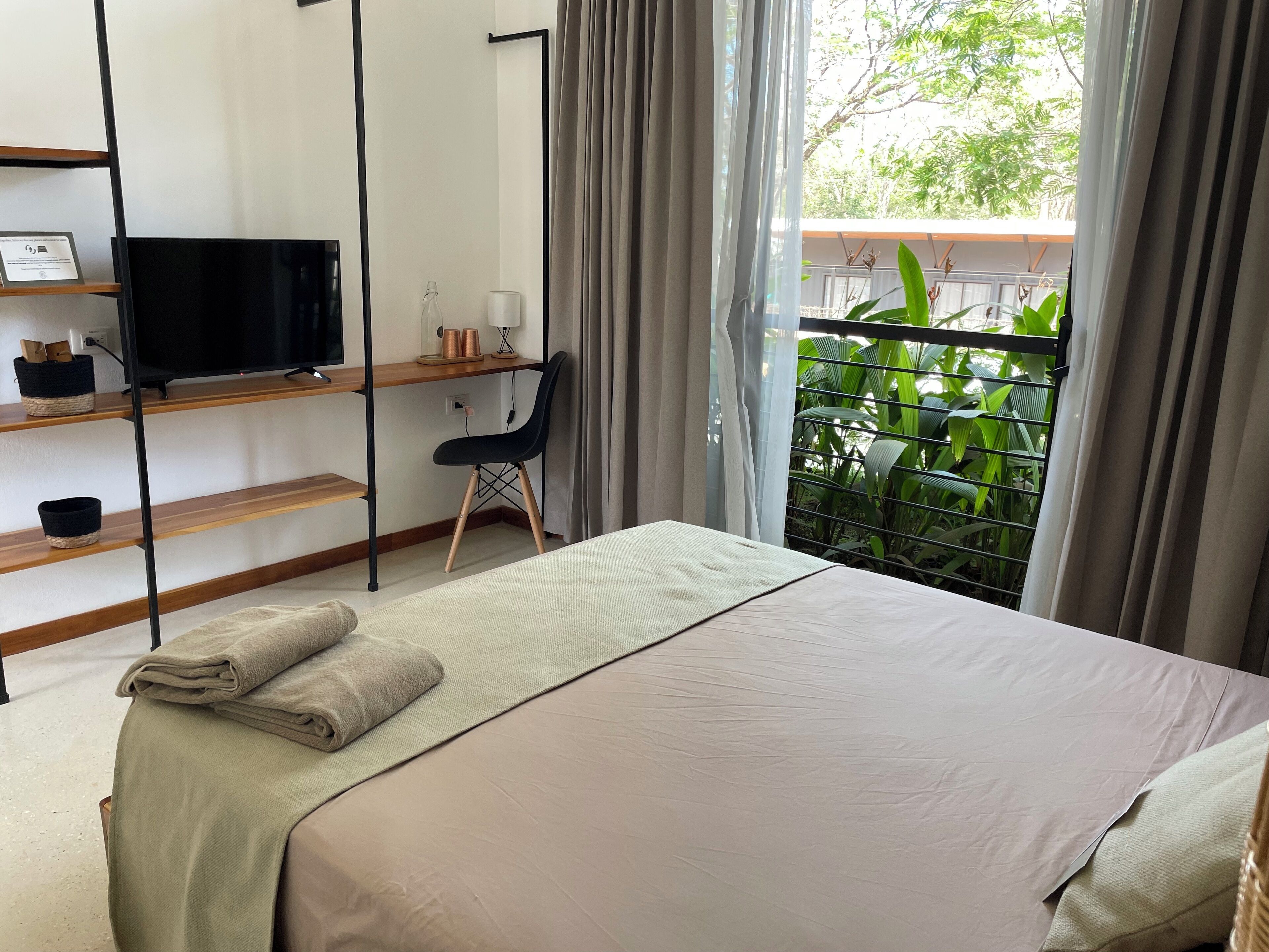 Un dormitorio con cama, escritorio, silla y televisor.