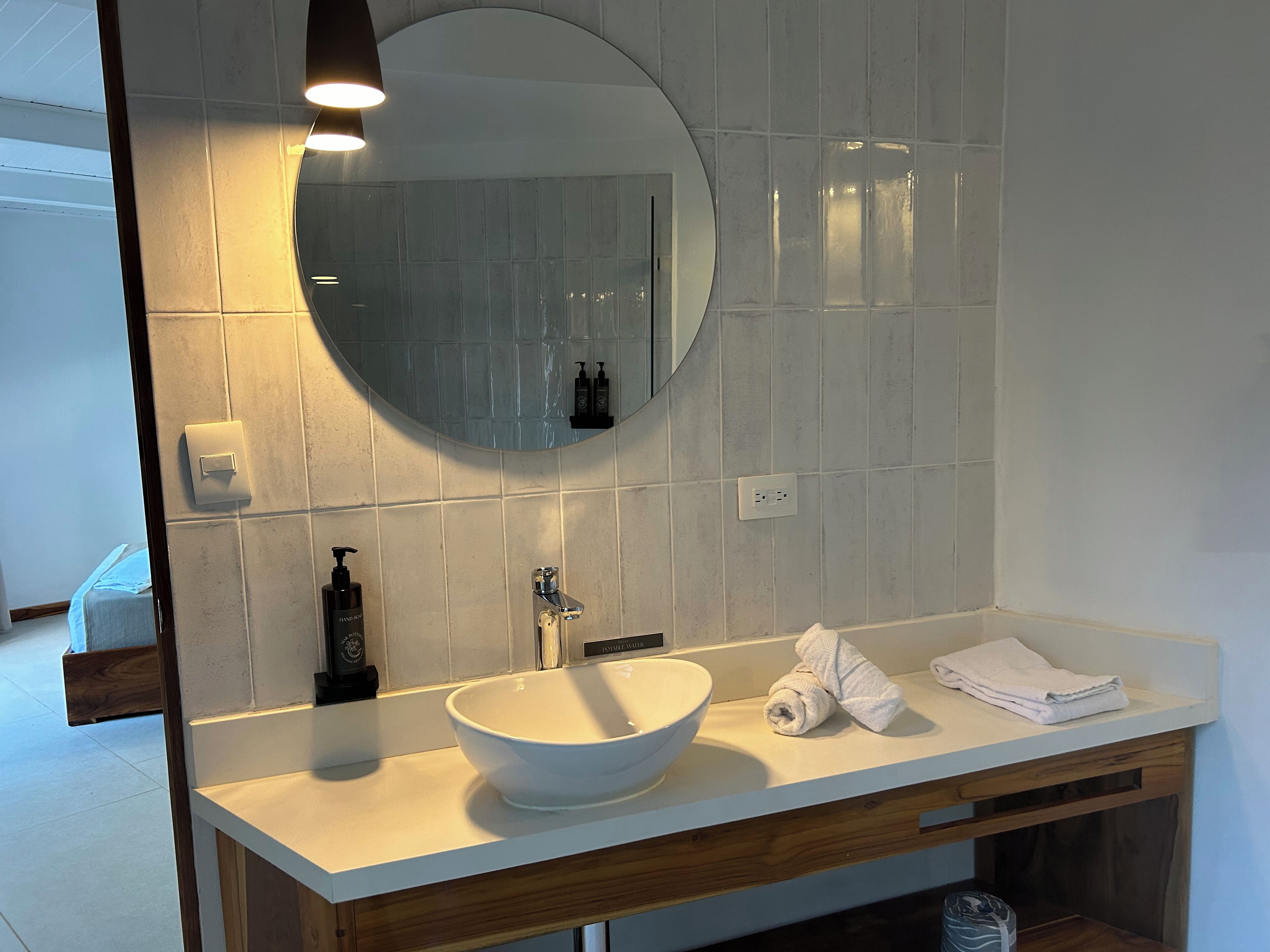 Une salle de bain moderne avec un lavabo blanc, un miroir rond et un meuble-lavabo en bois.