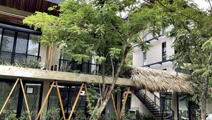 A modern building with a staircase, a thatched roof structure, and surrounding greenery. - Mar Botánico - Avellanas Beach Hotel (Veintisiete de Abril)