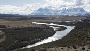 Une rivière serpente à travers une vallée, avec des montagnes en arrière-plan.