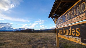 Un panneau indiquant le camping Serrano, avec une vue sur les montagnes en arrière-plan.