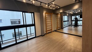 A spacious room with large windows, wooden flooring, and exercise equipment. - Studio em Perdizes - em frente a PUC (São Paulo)
