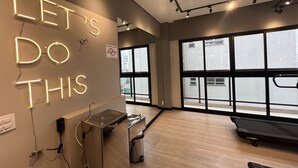 A modern gym with a motivational neon sign, large windows, and exercise equipment. - Studio em Perdizes - em frente a PUC (São Paulo)